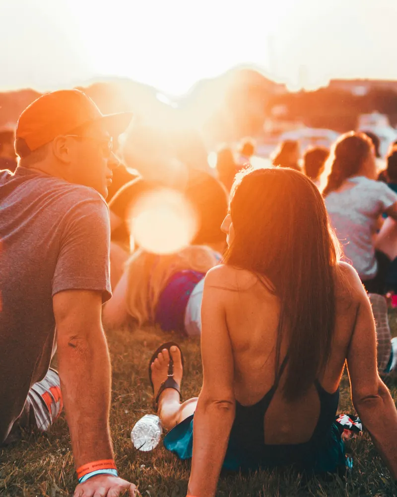 A couple sitting on the grass at sunset